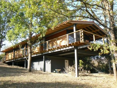 Vue extérieure en contre-bas d'une maison en bois dans la pente sur pilotis réalisée par Acedo Architecte