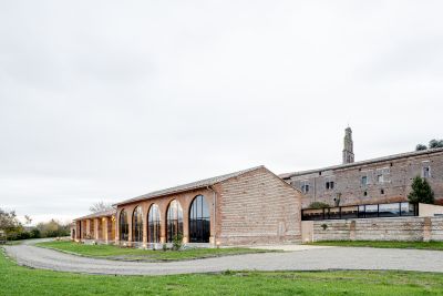 Vue du corps de bâtiment rénové et de l’extension émergeant au-dessus du mur d’enceinte - Copyright : Antoine Huot, OECO Architectes